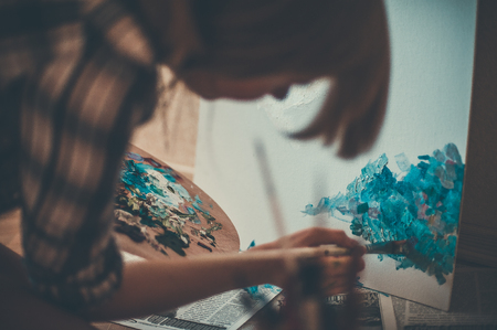teen girl painter drawing portrait with oil paints, professional painter at work over white backgroundの写真素材