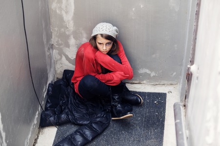 Homeless girl sitting on the floorの写真素材