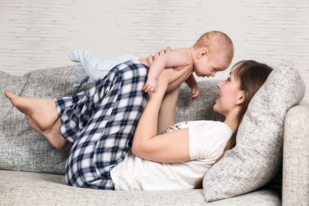 Happy mother playing with her cute loving baby at homeの写真素材