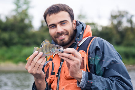 Mid adult fisherman on holidays on river, relaxing and fishing trout. Focus on fisher