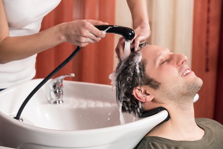 Washing man hair in beauty parlour hairdressing salonの写真素材