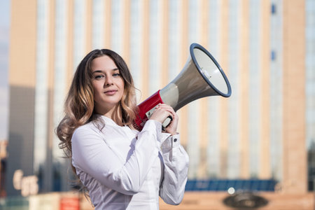 Stylish businesswoman holding a megaphone outdoorsの写真素材