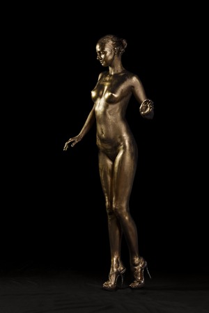 Golden statue of Valkyrie concept  Arty portrait of model with golden healthy skin and shiny lashes  Perfect sporty body  Studio shotの写真素材