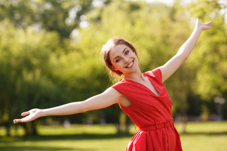 Adorable summer young woman in red dress, carefree dancing enjoying natureの写真素材