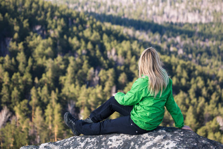 Young woman sitting on a rock and looking to the clouds の写真素材
