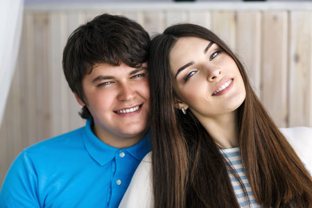 Smiling beautiful couple sitting on a sofa looking at the camera