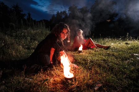 Portrait of dangerous woman witch with fire ball and dark make upの写真素材