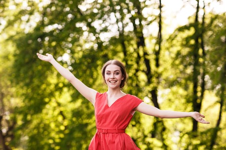 Adorable summer young woman in red dress, carefree dancing enjoying natureの写真素材