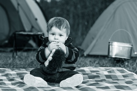 little boy playing with a teddy bear in the grassの写真素材