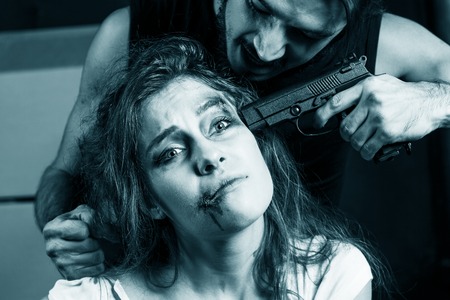 Crime. Beautiful girl kidnapped by criminals. Terrorist is threatening hostages with a gun.の写真素材