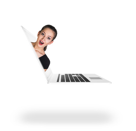A pretty surprised woman coming out of laptop computerの写真素材