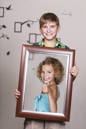 Happy brother holding portrait with his sister each is located inside her own frameの写真素材