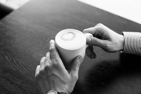 Businessman taking a break at the office as he enjoys a cup of hot aromatic coffee, close up view of...