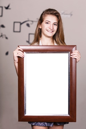 Happy young girl holding portrait frame with empty spaseの写真素材