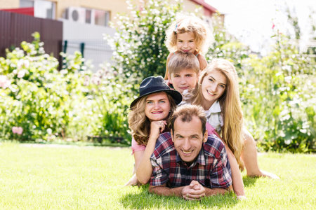 Happy family lying on the grass, having weekend in summer parkの写真素材