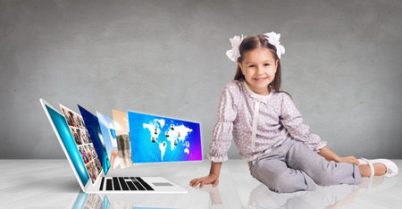 Laptop with many screens stand on the floor and child beside.