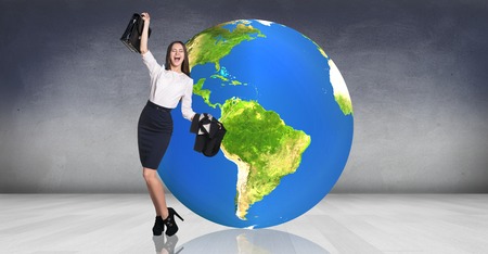 Business woman stands near big earth ball in the gray room. の写真素材