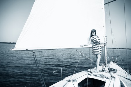 Young beautiful woman posing on the yacht in sunlight dayの写真素材