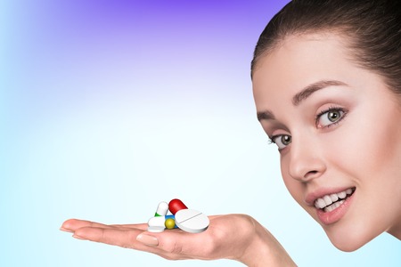 Young woman and drug capsules and pills in hand on the blue backgroundの写真素材
