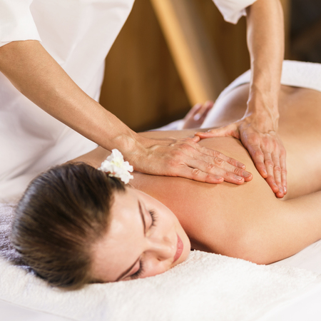 Young beautiful girl lying on massage table and enjoying massage.の写真素材