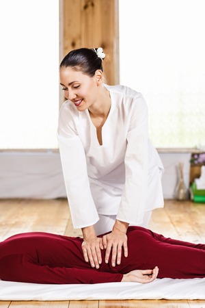 Young masseur massaging young woman back in wooden roomの写真素材