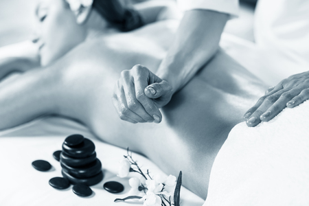 Young beautiful woman enjoying massage on the table at spa centerの写真素材