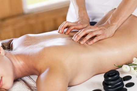 Young beautiful woman enjoying massage on the table at spa centerの写真素材