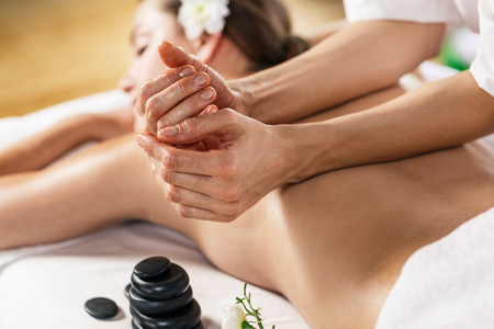 Young beautiful woman enjoying massage on the table at spa centerの写真素材