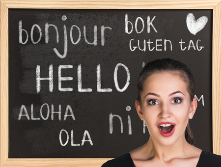 Woman near words hello in different languages on chalkboardの写真素材