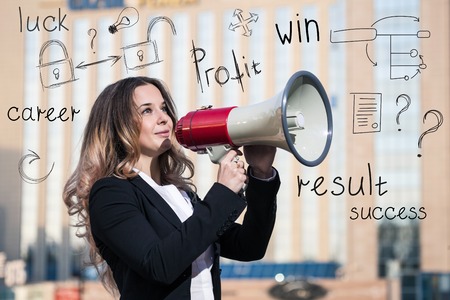 Stylish businesswoman holding a megaphone outdoors with icons overheadの写真素材