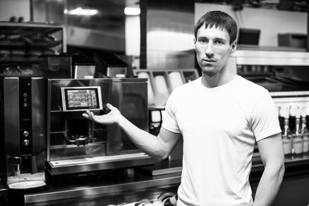 Young barista standing and show professional coffee maker on backgroundの写真素材