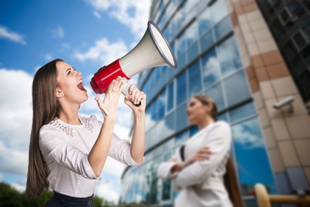 Portrait of beautiful young business woman with megaphone outdoors backgroundの写真素材