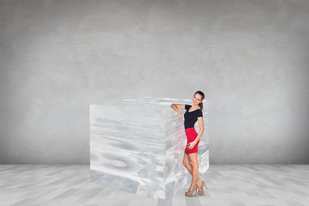 Business woman near big ice cube in the gray roomの写真素材