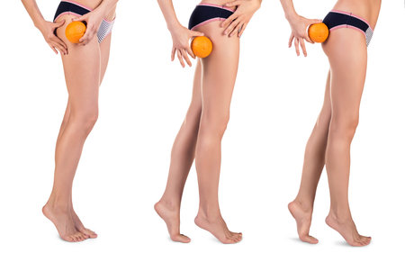 Young woman in underwear with orange showing absence of cellulite and perfect body over white backgroundの写真素材