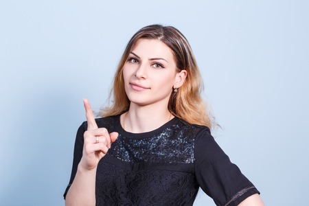 Young beautiful woman threaten finger on blue backgroundの写真素材