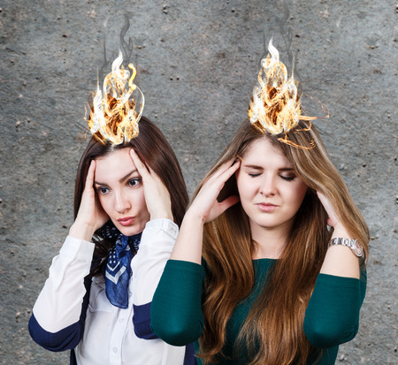 Two women with a strong headache on the gray wall backgroundの写真素材