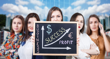Young woman holds chalkboard with financial graph on the city backgroundの写真素材