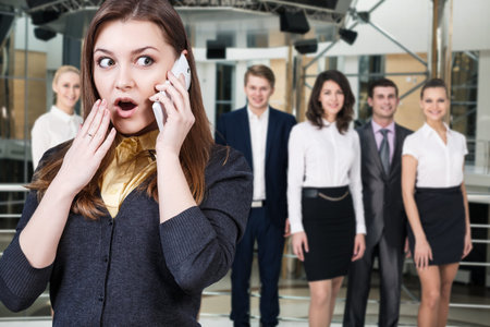 Young woman speak on the phone on the blurred business people backgroundの写真素材