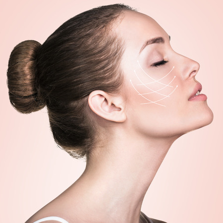 Close-up portrait of young, beautiful and healthy woman with arrows on her face. Spa, surgery, face lifting and make-up conceptの写真素材