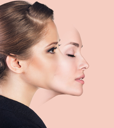 Young woman taking off a mask over pink backgroundの写真素材