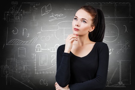 Thoughtful woman over school chalk board backgroundの写真素材