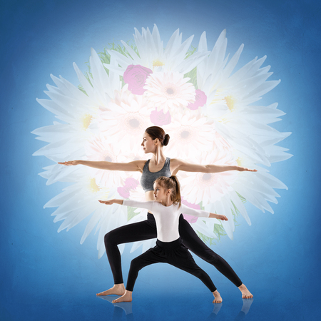 Woman and her daughter doing yoga exercise isolated over white backgroundの写真素材