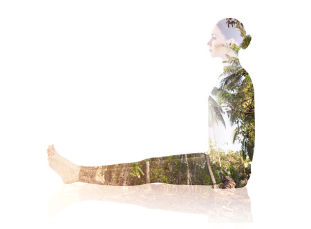 Double exposure of woman doing yoga exercise with the foliage of treesの写真素材