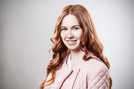 Smiling redhead girl in pink jacketの写真素材