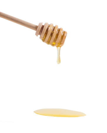 Honey is dripping from the wooden spoon.の写真素材