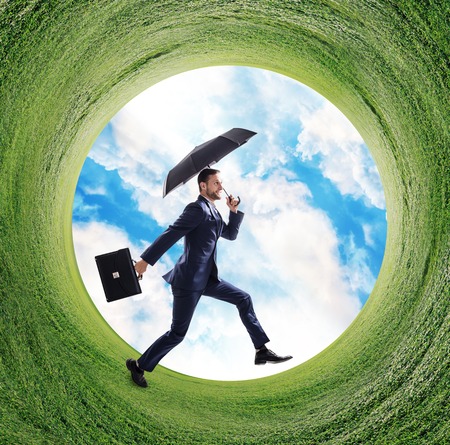 Businessman running into green grass circle.の写真素材