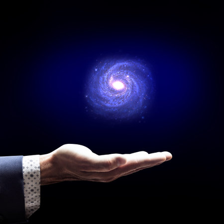 Businessman hand holding little galaxy.