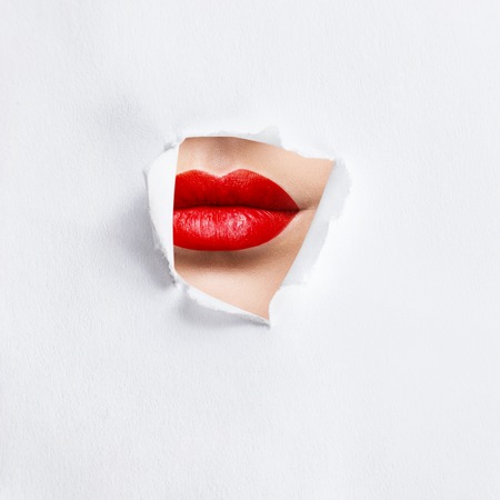 Plump lips of red color in the slit of white paperの写真素材