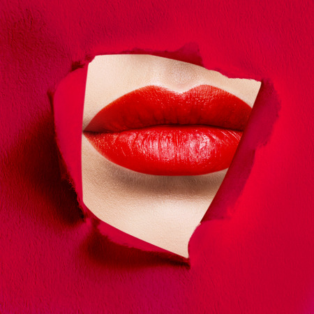 Plump lips of red color in the slit of white paperの写真素材