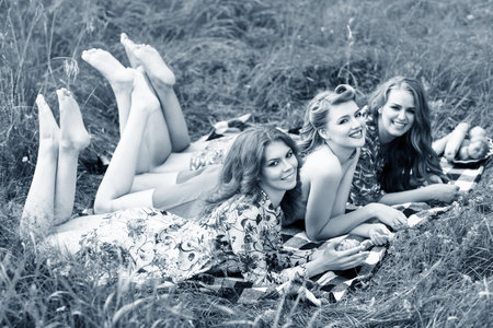 Young beautiful women lying on plaid in summer park.